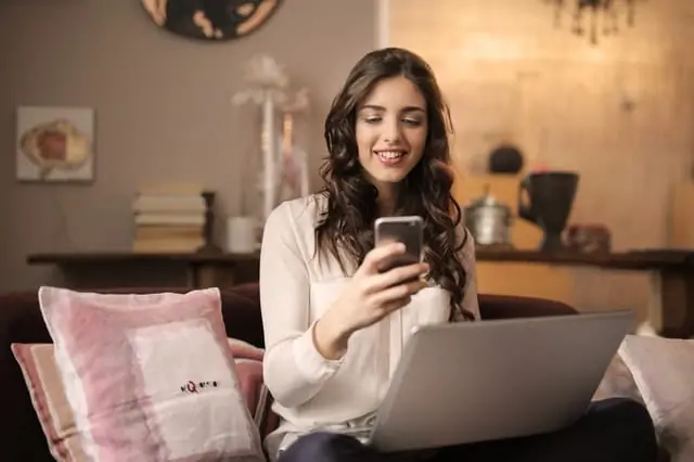 Une femme utilisant son téléphone et son ordinateur portable pour passer de rencontres virtuelles à des rencontres réelles sur un site de rencontre.